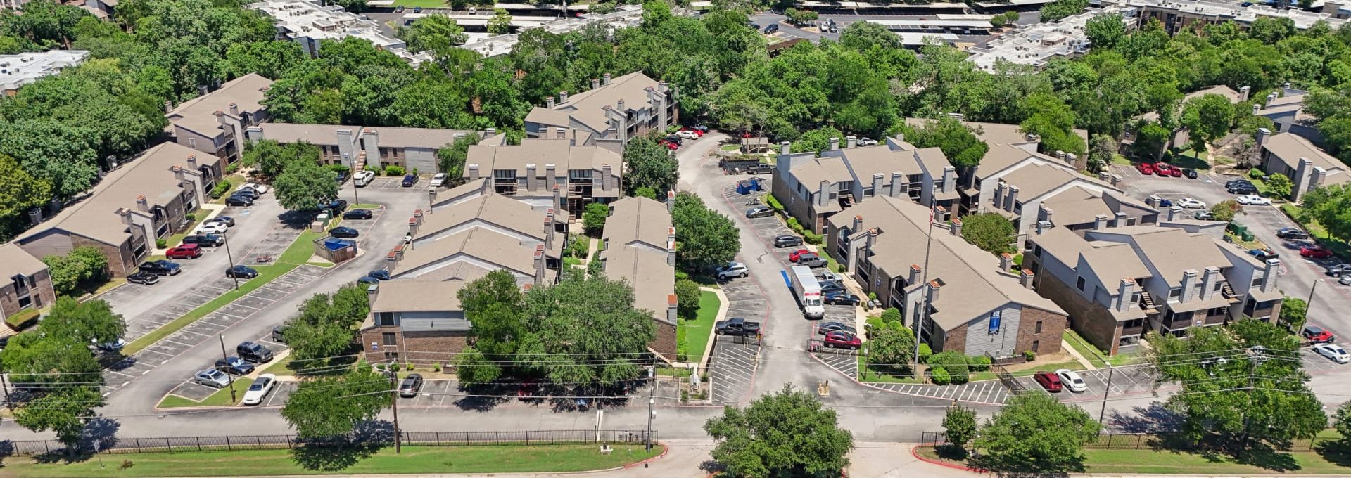 an aerial view of a residential neighborhood with trees and cars at The Cross Creek Apartments