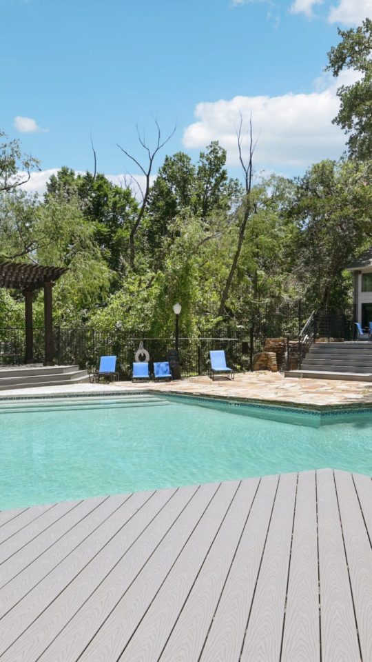 a pool with a deck and a deck chair at The Cross Creek Apartments