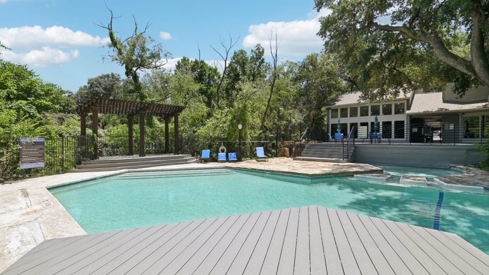 a pool with a deck and a deck chair at The Cross Creek Apartments