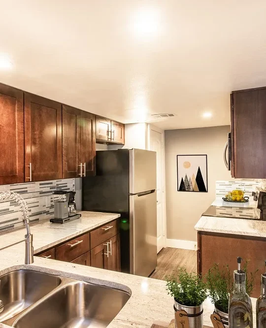 a kitchen with stainless steel appliances and wood cabinets at The Cross Creek Apartments